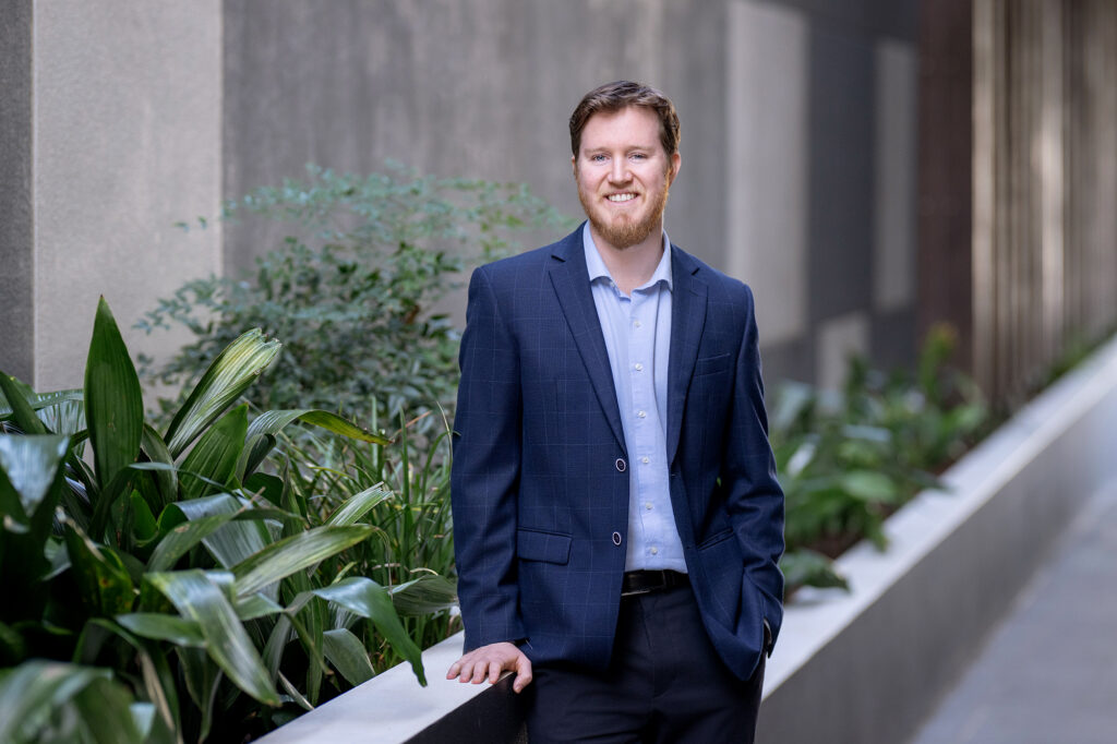 Alexander Carey-Foster, Solicitor at Hall Payne Lawyers, smiling in front of plants