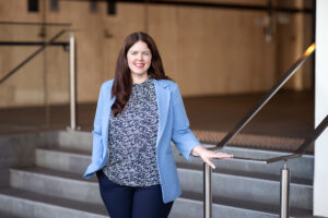 Carmen Stalley, Solicitor at Hall Payne Lawyers, smiling in front of a staircase