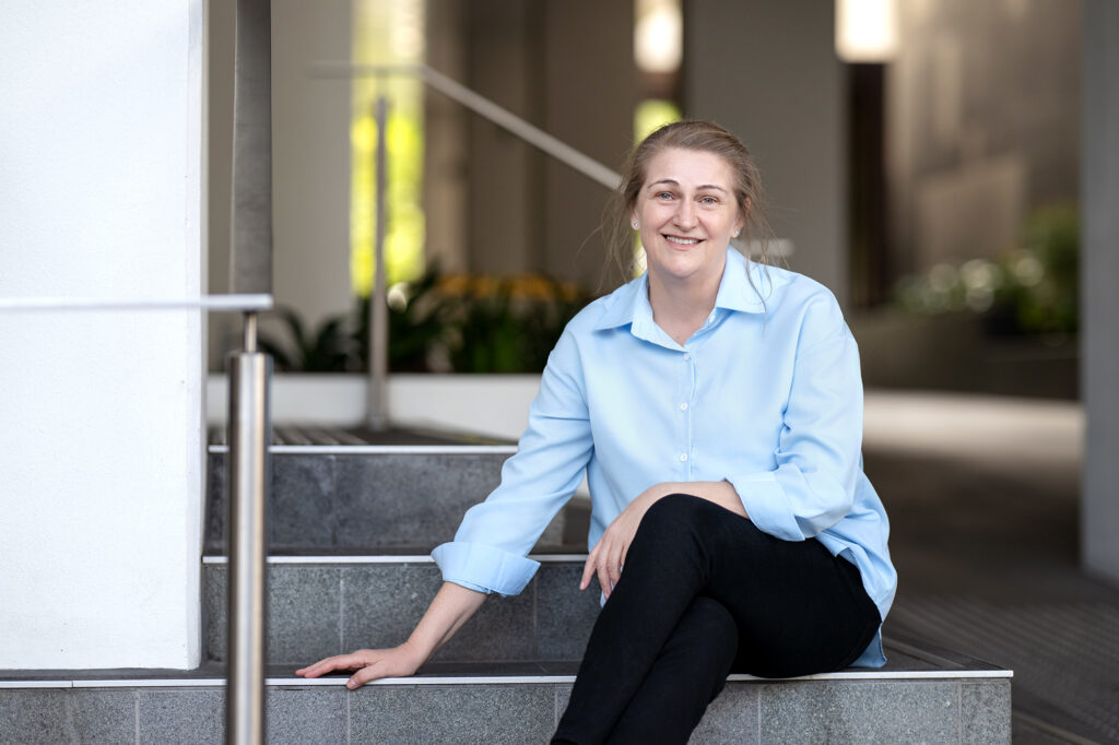 Sarah Cavanagh, Paralegal with Hall Payne Lawyers, smiling sitting on steps