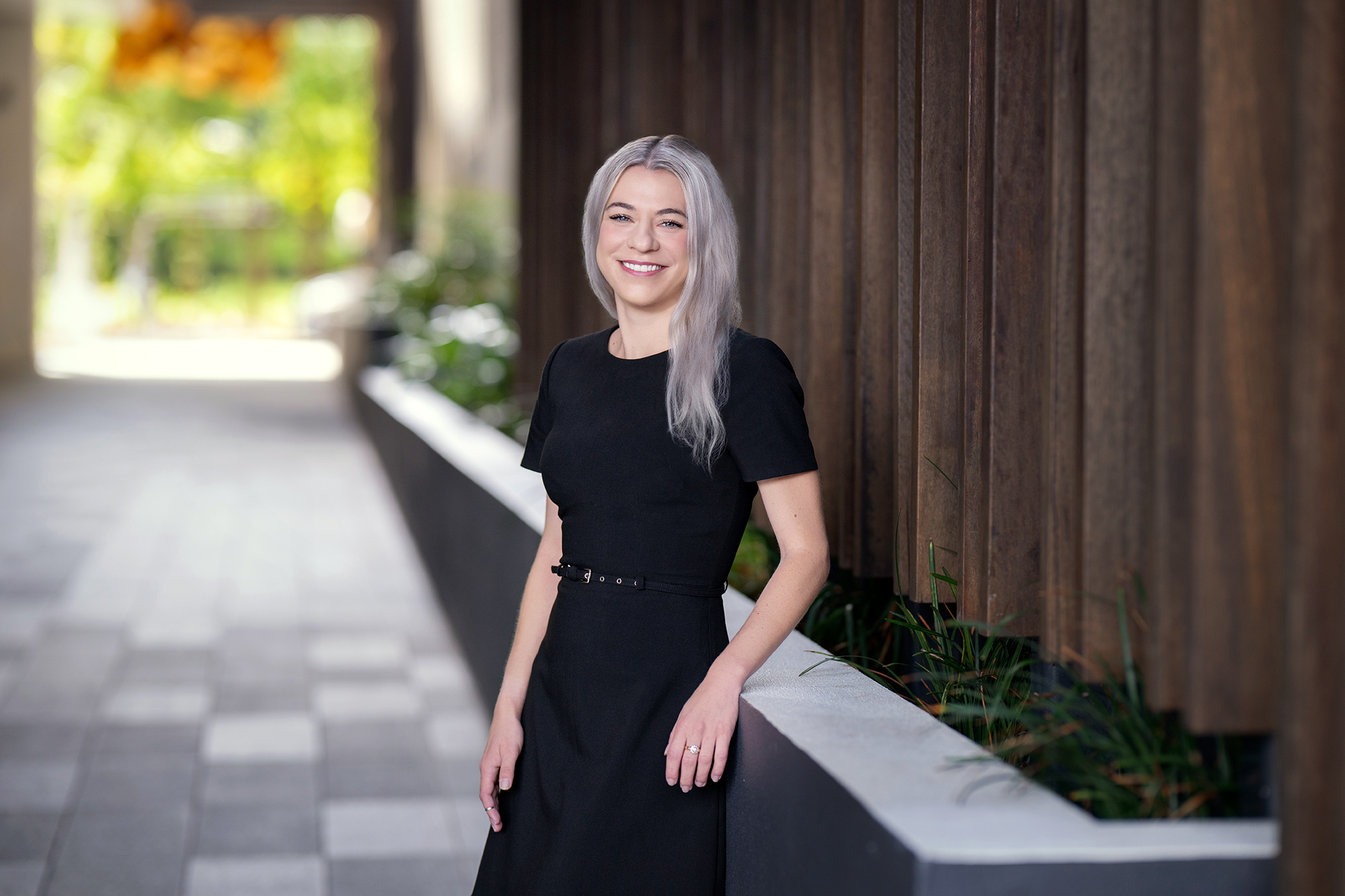Jeri Murray - Hall Payne Lawyers - smiling and leaning against wall planter